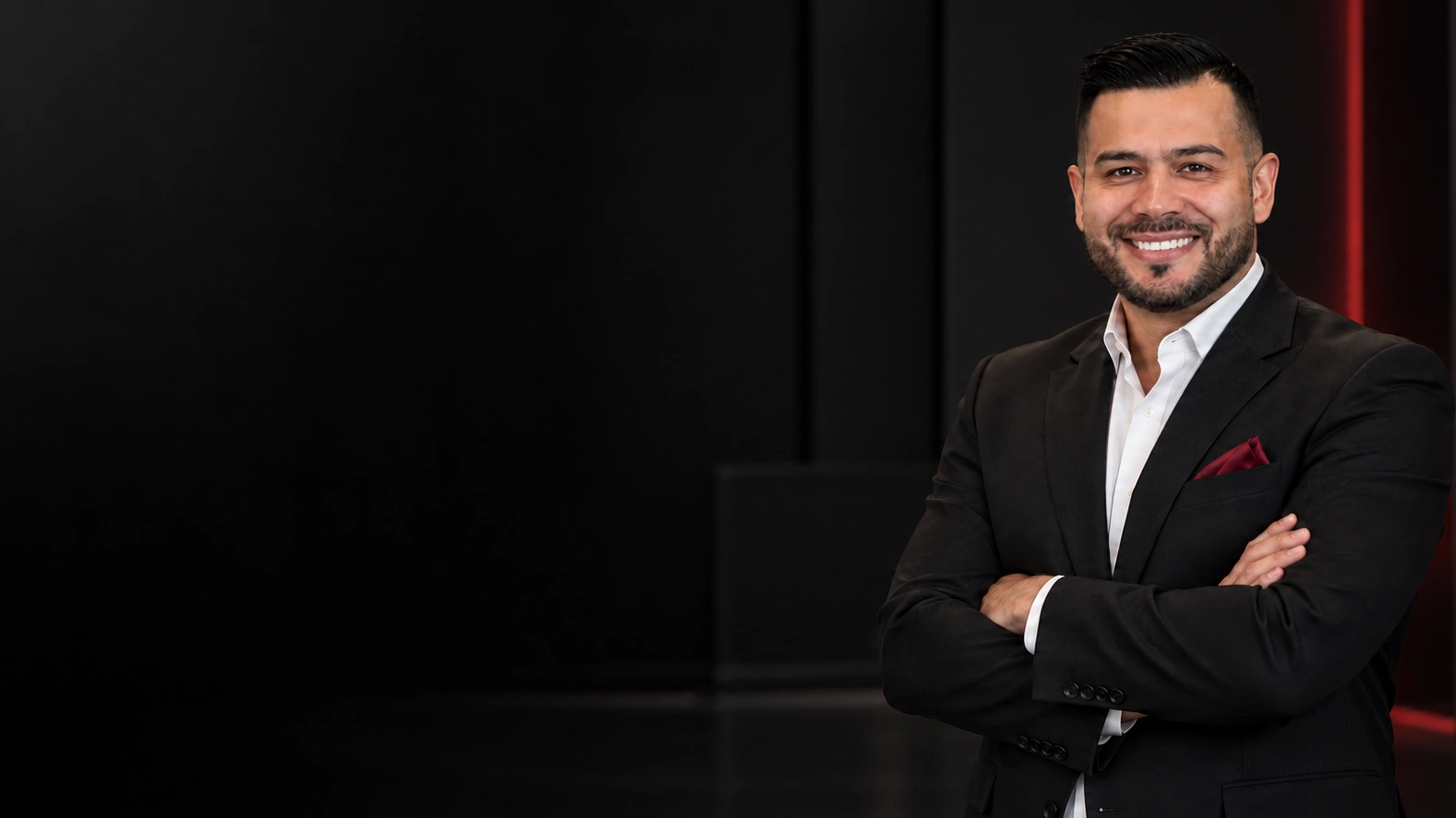 Robert Casillas in a black suit with folded arms against a dark executive interior